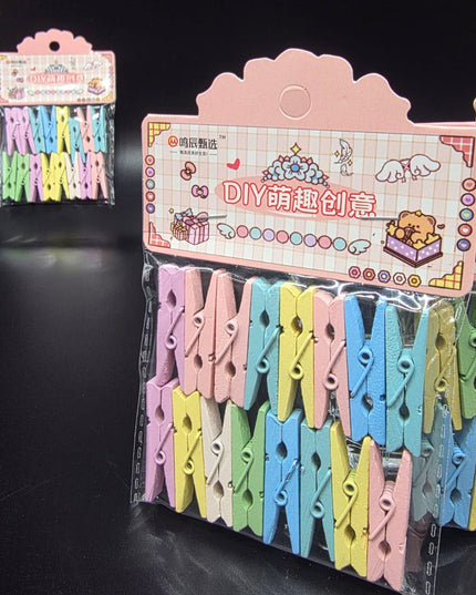 Colorful clothespins in a clear plastic package with a pink display stand on a black background.