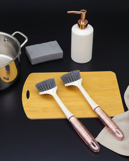Two scrub brushes with red handles on a wooden cutting board against a dark background