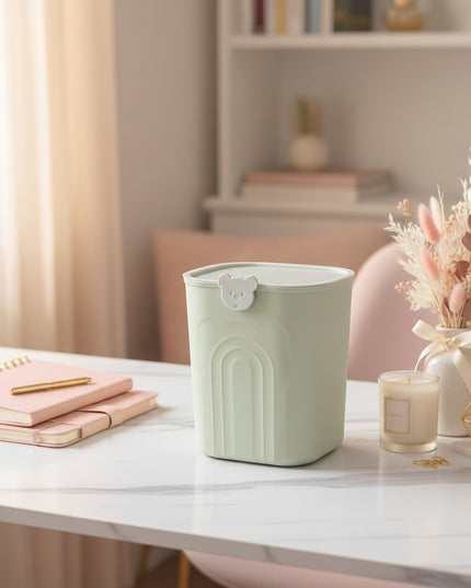 Light green trash bin with a bear-shaped handle on a white surface.