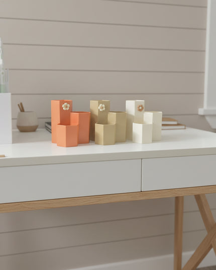 Person sitting behind a display of geometric ceramic vases in orange and beige.
