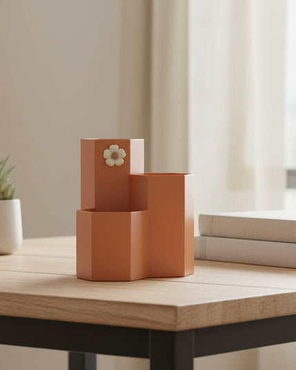 Brown pen holder with a decorative flower on a white surface