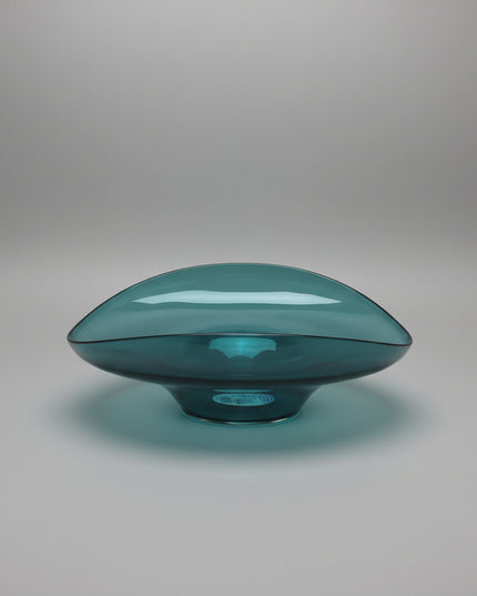 Teal glass bowl on a white surface with a white background