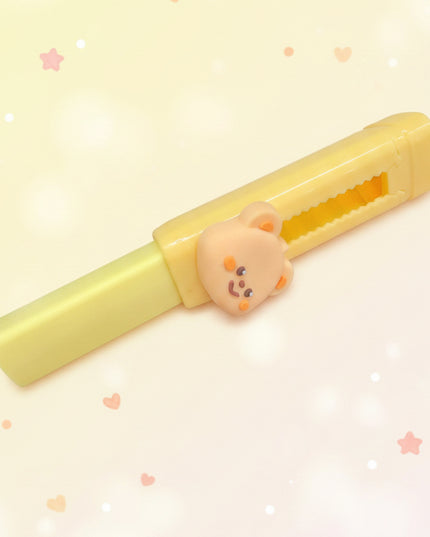 Yellow plastic tool with a bear-shaped handle on a dark surface