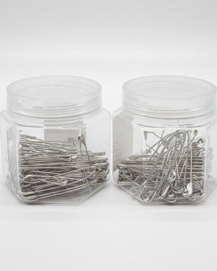 Two clear plastic jars filled with metal hairpins on a black background