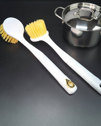 Two white cleaning brushes with yellow bristles on a black background